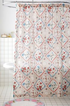 a bathroom with a floral shower curtain and rug