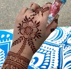 a woman's hand with henna tattoos holding a tube of toothpaste