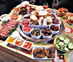 a table filled with lots of food and wine glasses on top of it, including cucumbers