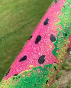 a close up view of a pink and green painted bicycle handlebar with black dots