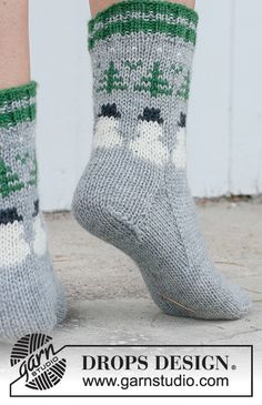 the legs of a person wearing gray socks with green and white designs on them, standing in front of a door