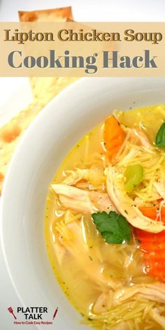 a white bowl filled with chicken soup on top of a table next to crackers