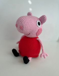 a crocheted pink pig sitting on top of a white table next to a red object