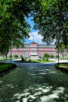 a large building with many windows and trees in front of it on a sunny day