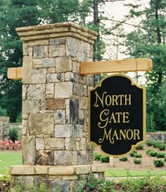 a sign for the north gate manor in front of some trees