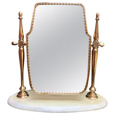 a large mirror sitting on top of a white marble table next to two golden metal poles