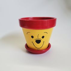 a winnie the pooh planter is sitting on a white surface with a red rim