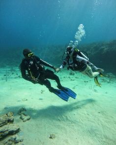 two people in scuba gear are swimming on the ocean floor