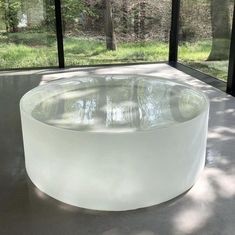 a large white circular table sitting on top of a cement floor in front of a window