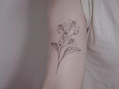 a black and white photo of a flower tattoo on the left upper half of the arm