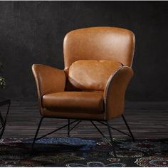 a brown leather chair sitting on top of a wooden floor next to a black wall