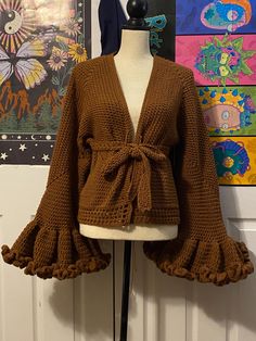 a mannequin wearing a brown cardigan with ruffles on the sleeves