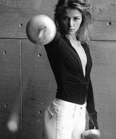 black and white photograph of a woman holding an apple in front of a wooden wall