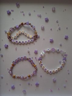 three beaded bracelets are displayed on a white surface with beads scattered around them