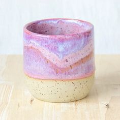 a purple and white cup sitting on top of a wooden table