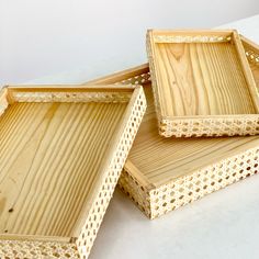 three wooden trays sitting next to each other on a white counter top, one with holes in it