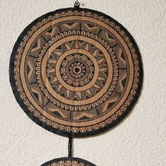 two circular wooden wall hangings with designs on the top one is black and brown