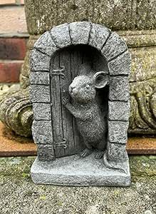 a statue of a mouse in front of a stone door with a cross on it