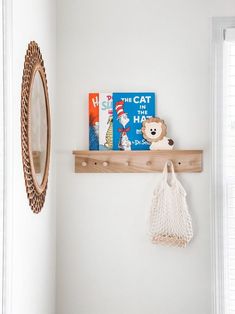 there is a cat on the shelf with a book and a bag next to it