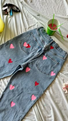 a pair of blue jean shorts with hearts painted on them sitting on a white sheet