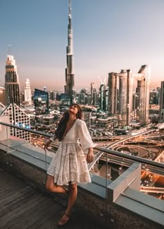 a woman standing on top of a building next to a railing with buildings in the background