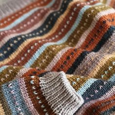 a multicolored crocheted blanket laying on top of a bed