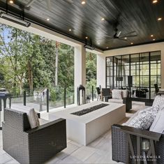 an outdoor living area with wicker furniture and large windows