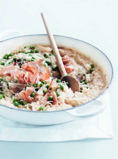 a bowl filled with rice, peas and meat on top of a white table cloth