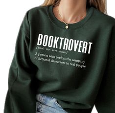 a woman wearing a green sweatshirt with the words booktrovert printed on it