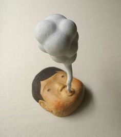 a small statue of a man's head with a cloud coming out of it