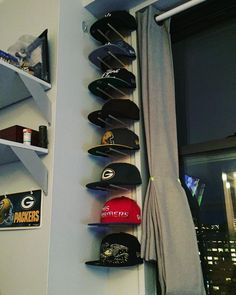 hats are hanging on the wall next to a window