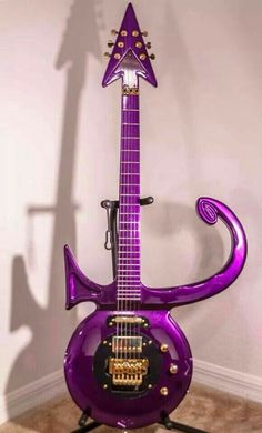 a purple guitar sitting on top of a stand