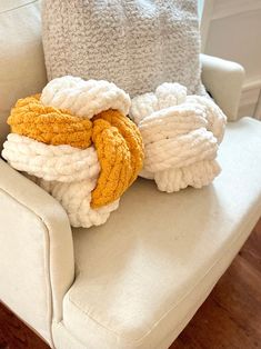 a pile of towels sitting on top of a white chair next to a pillow and blanket