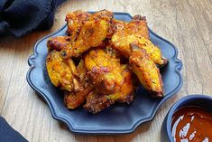 chicken wings on a blue plate next to dipping sauce