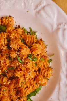 a white plate topped with pasta covered in sauce and parmesan cheese sprinkled on top