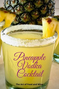 a pineapple vodka cocktail in a glass with powdered sugar on the rim and garnishes