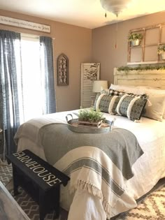 a bedroom with a large bed and pillows on top of the bedspread in front of a window