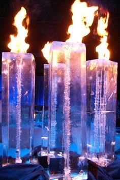 three ice cubes with flames burning in the middle on a blue cloth covered table