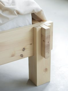 a close up of a wooden bed frame with white sheets on the top and bottom