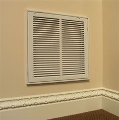 an air conditioner sitting on the side of a wall next to a carpeted floor