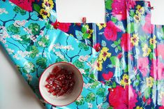 a bowl of jelly sitting on top of a blue flowered table cloth next to two pieces of paper