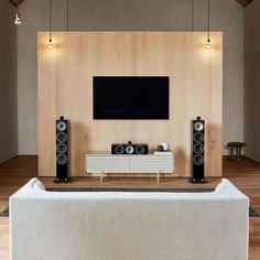 an entertainment center with speakers and a flat screen tv mounted on the wall above it