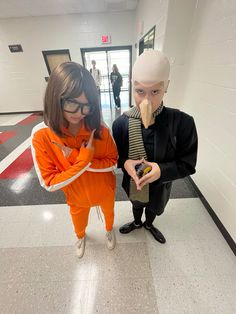 two people in orange jumpsuits standing next to each other and one person holding a cell phone