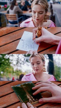 a woman sitting at a wooden table holding a piece of paper and looking at it