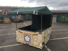 an outdoor food cart with a canopy on the top in a parking lot next to a building