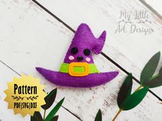 a purple felt witch hat sitting on top of a white wooden table next to green leaves