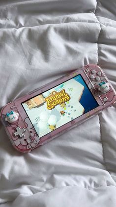 a pink nintendo wii game controller laying on top of a white bed sheet covered in sheets