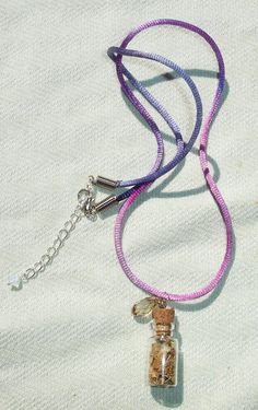 a purple lanyard with a glass bottle on it and a chain attached to it