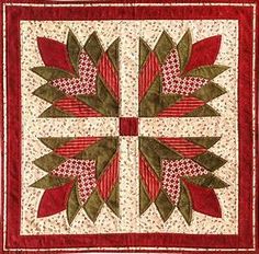 a quilted wall hanging with red and green leaves on the center, surrounded by white dots