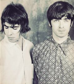 two young men standing next to each other in front of a gray wall with circles on it